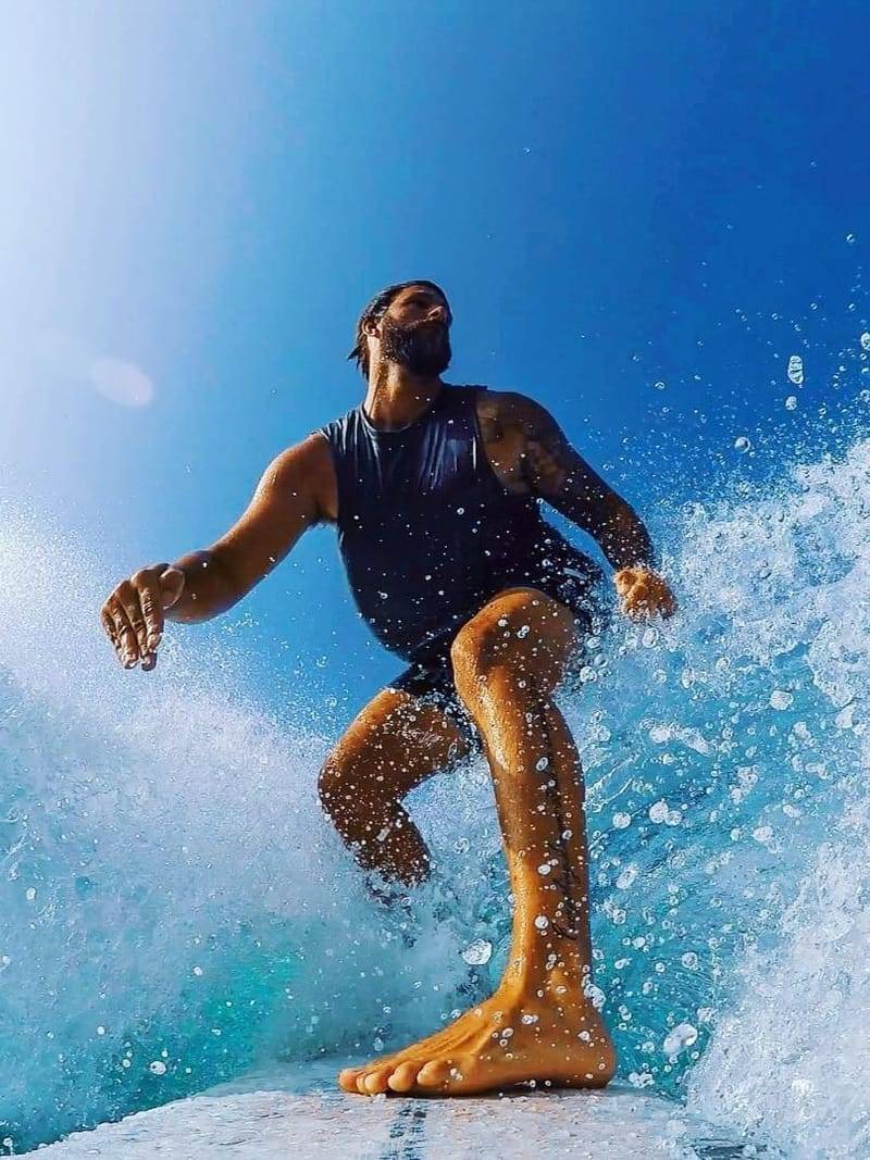 A surfer driving through spray on a clean wave, shot from the water
